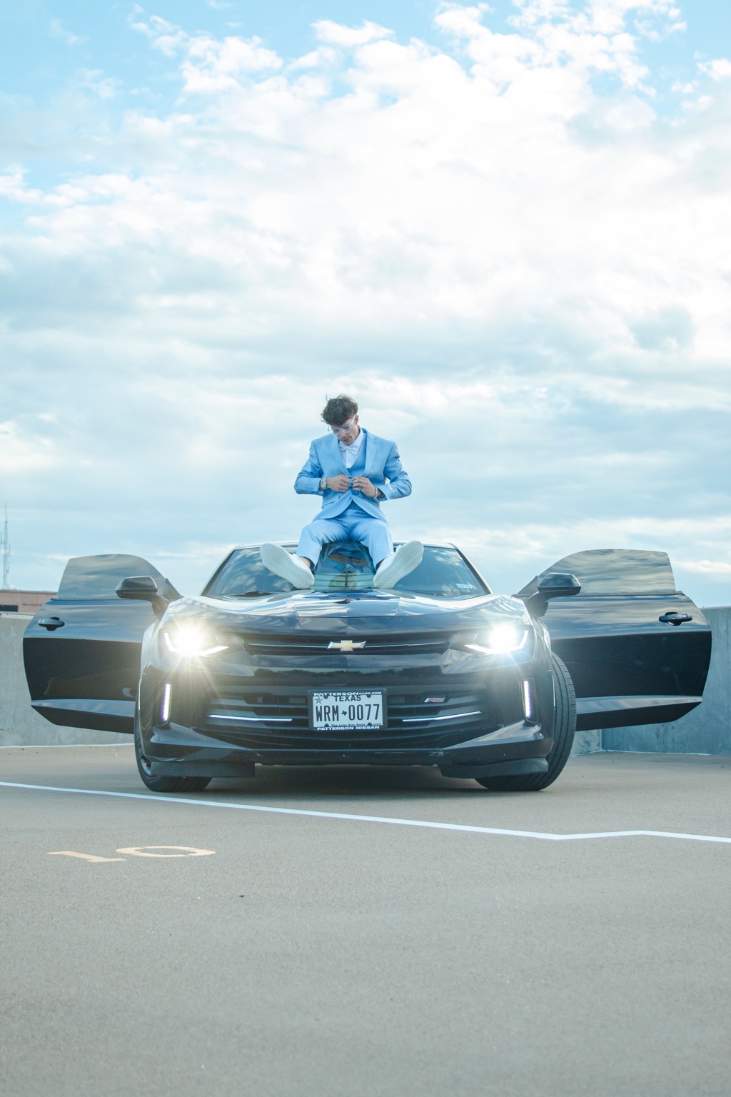 Portrait in a blue suit posed on a dark sports car