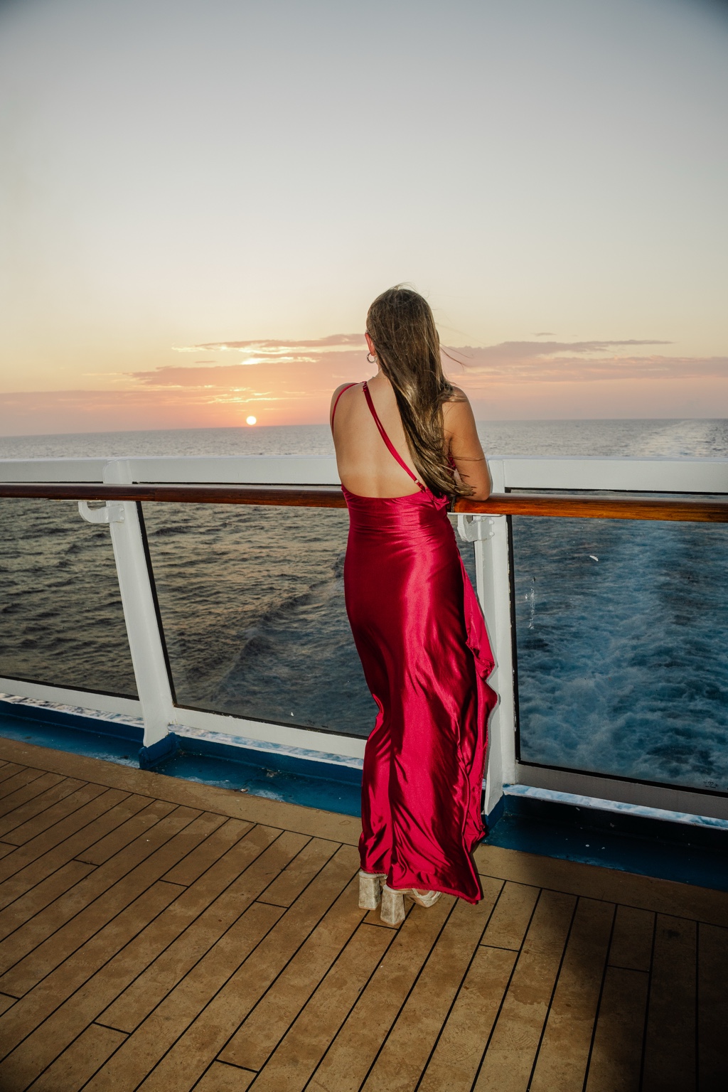 Portrait in a red dress looking toward an ocean sunset