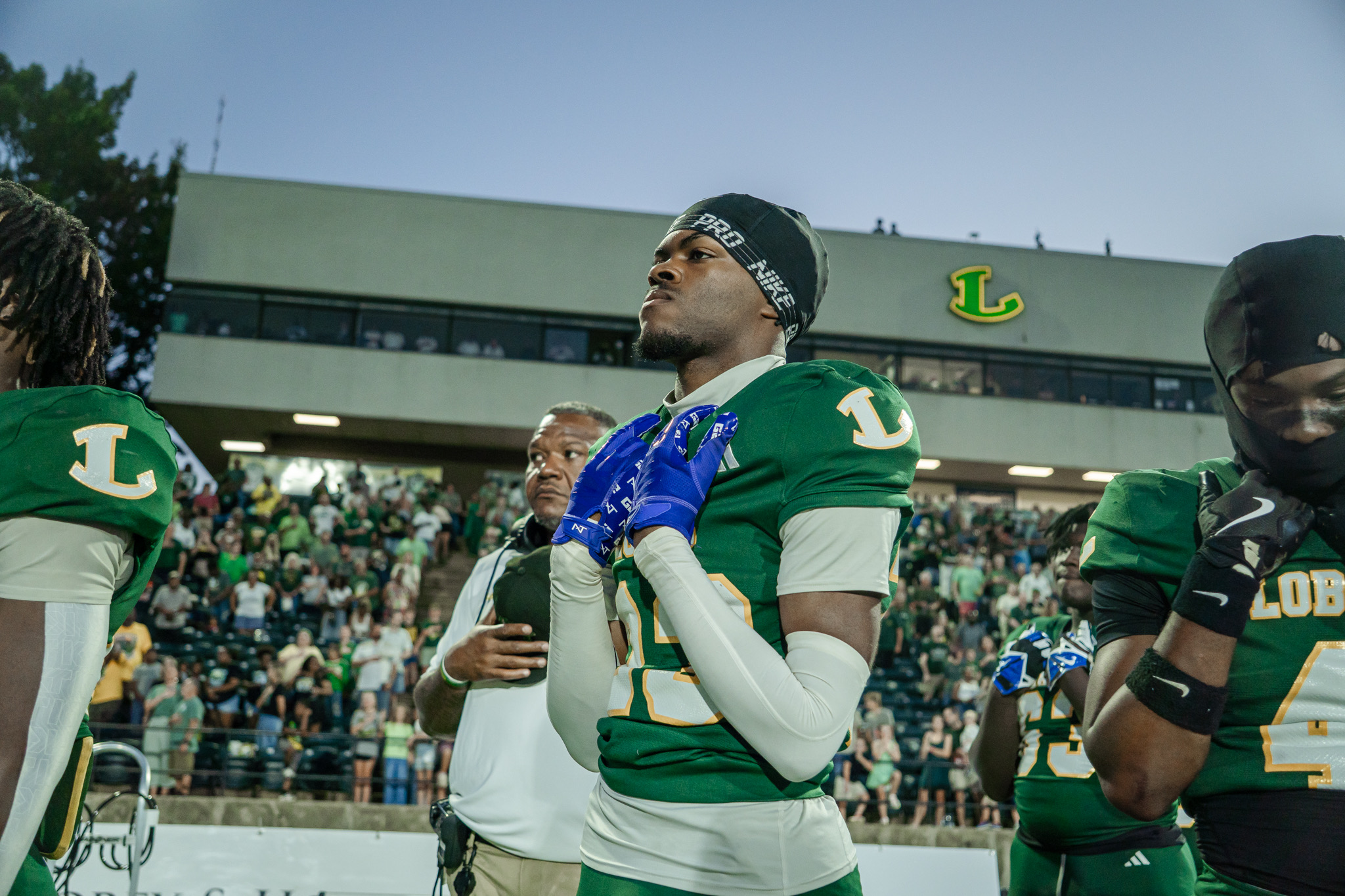 Longview player with blue gloves held to his chest in front of the home crowd