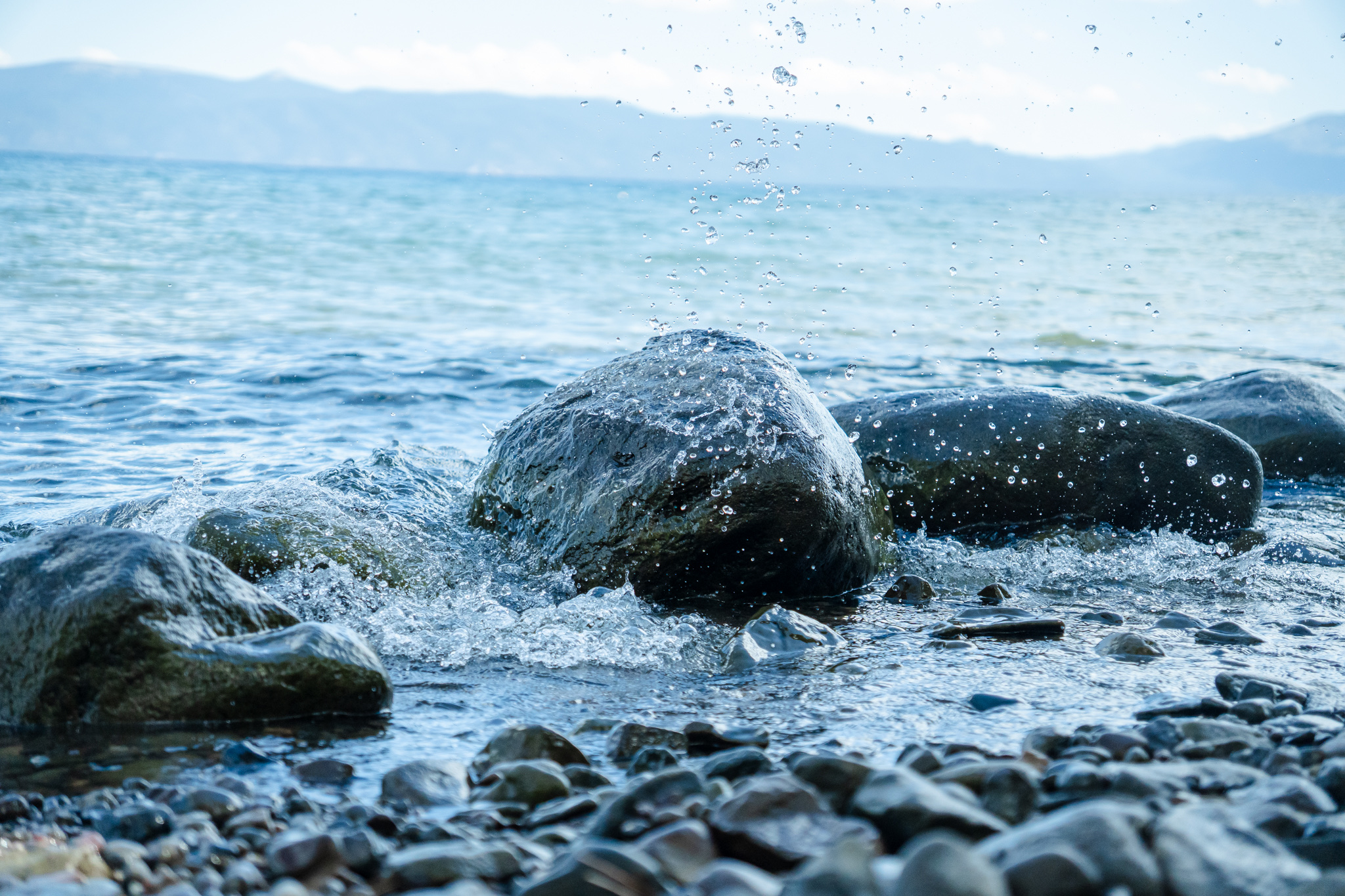 Lake Tahoe waves splashing over dark shoreline rocks